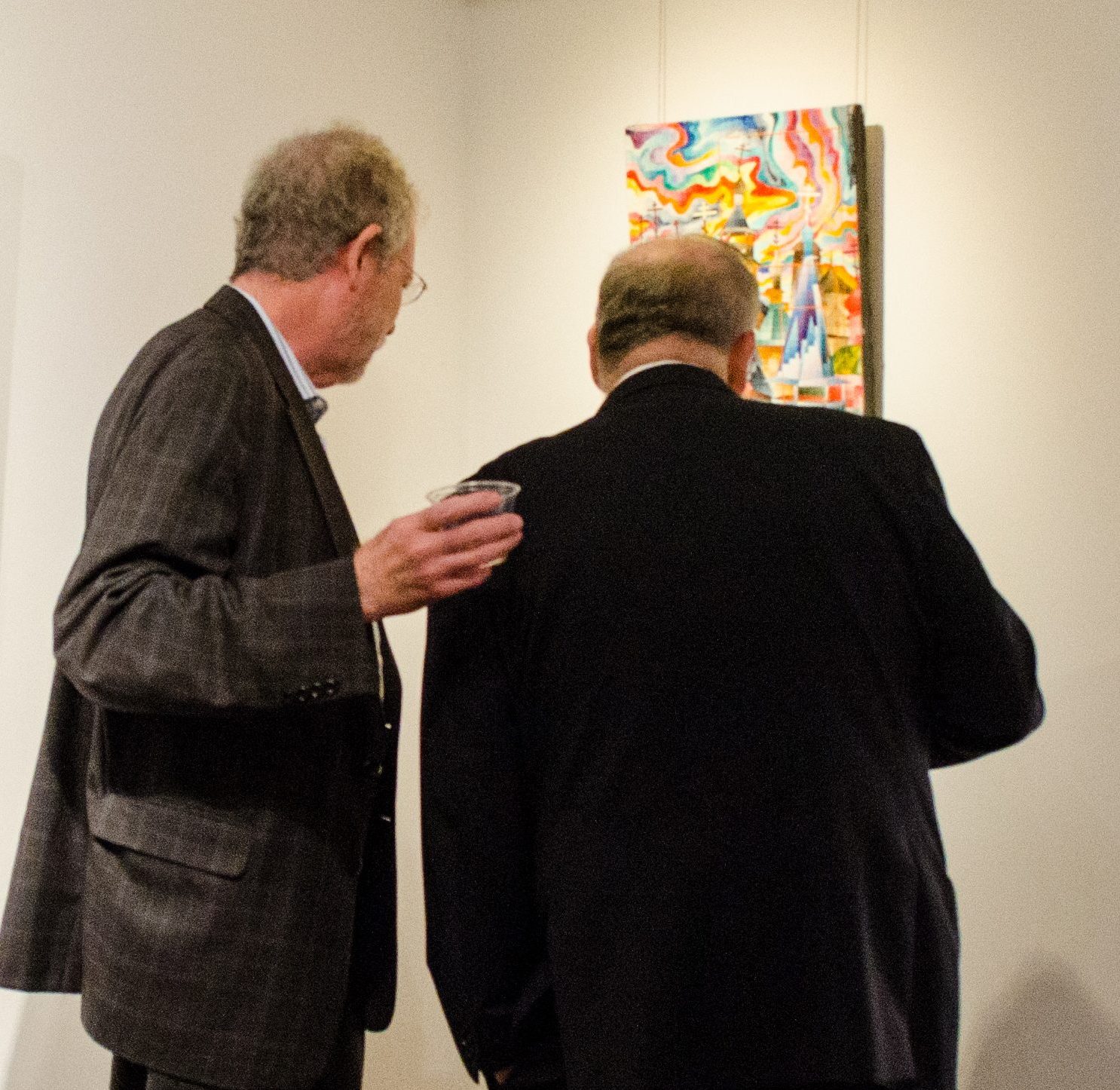 photo of two men standing and looking at art on the walls